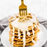 A gold fork in a stack of pancakes.