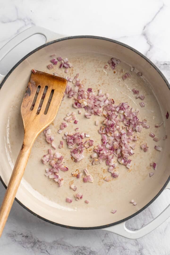 Overhead view of minced red onions cooking in skillet