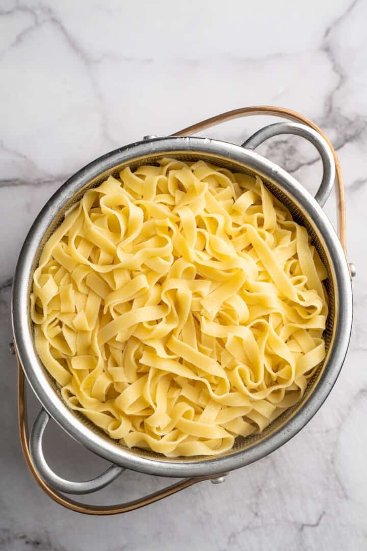 Overhead view of cooked fettuccine in colander