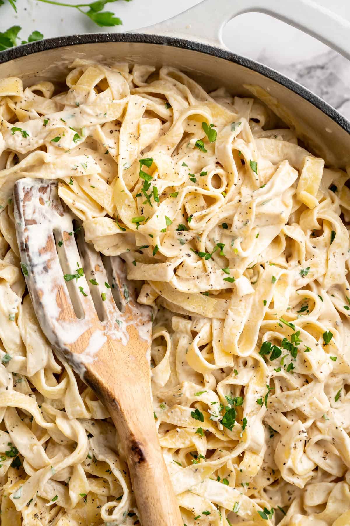 Skillet of vegan garlic Alfredo pasta with wooden spoon