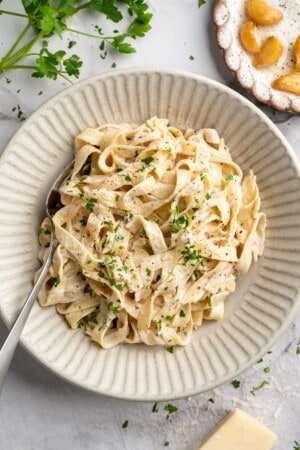 Overhead view of vegan garlic Alfredo pasta in bowl with spoon