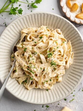 Overhead view of vegan garlic Alfredo pasta in bowl with spoon
