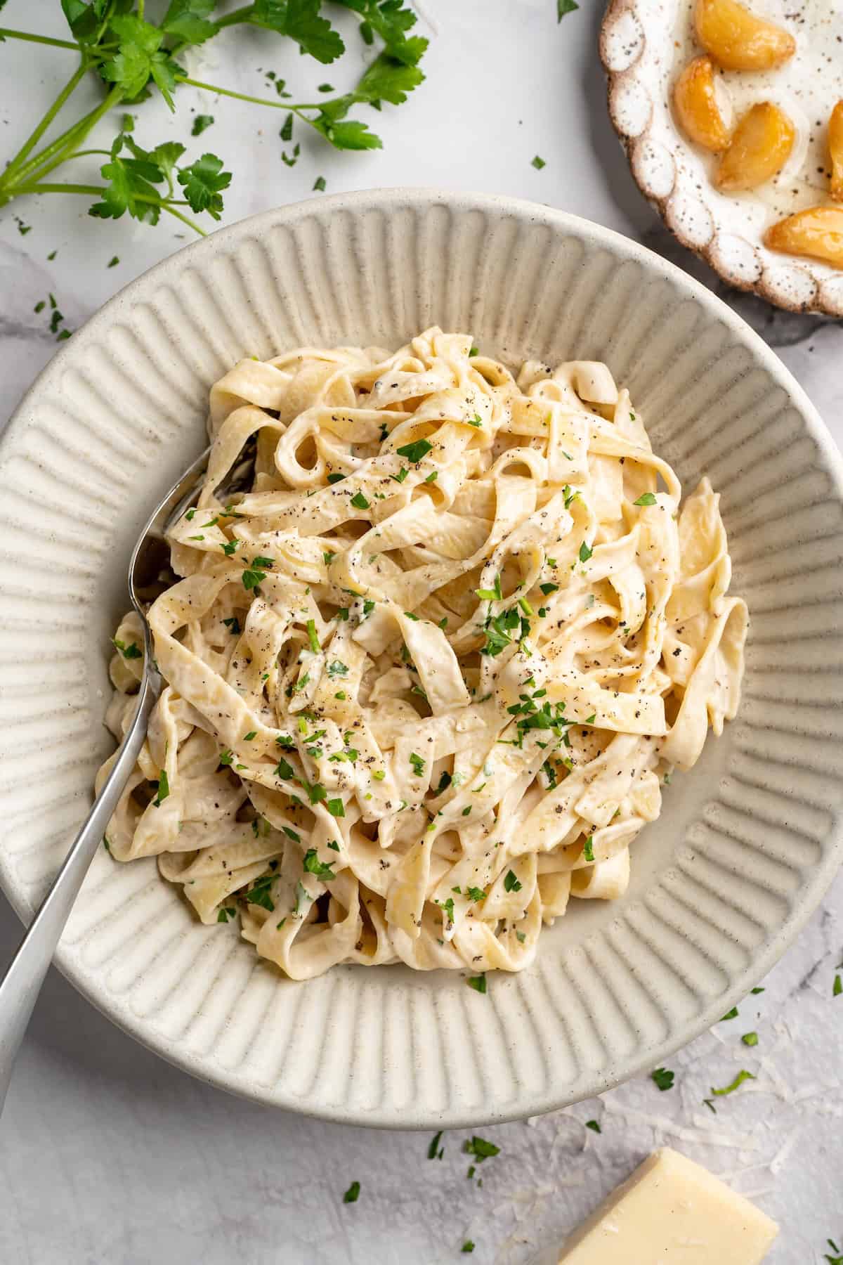 Overhead view of vegan garlic Alfredo pasta in bowl with spoon