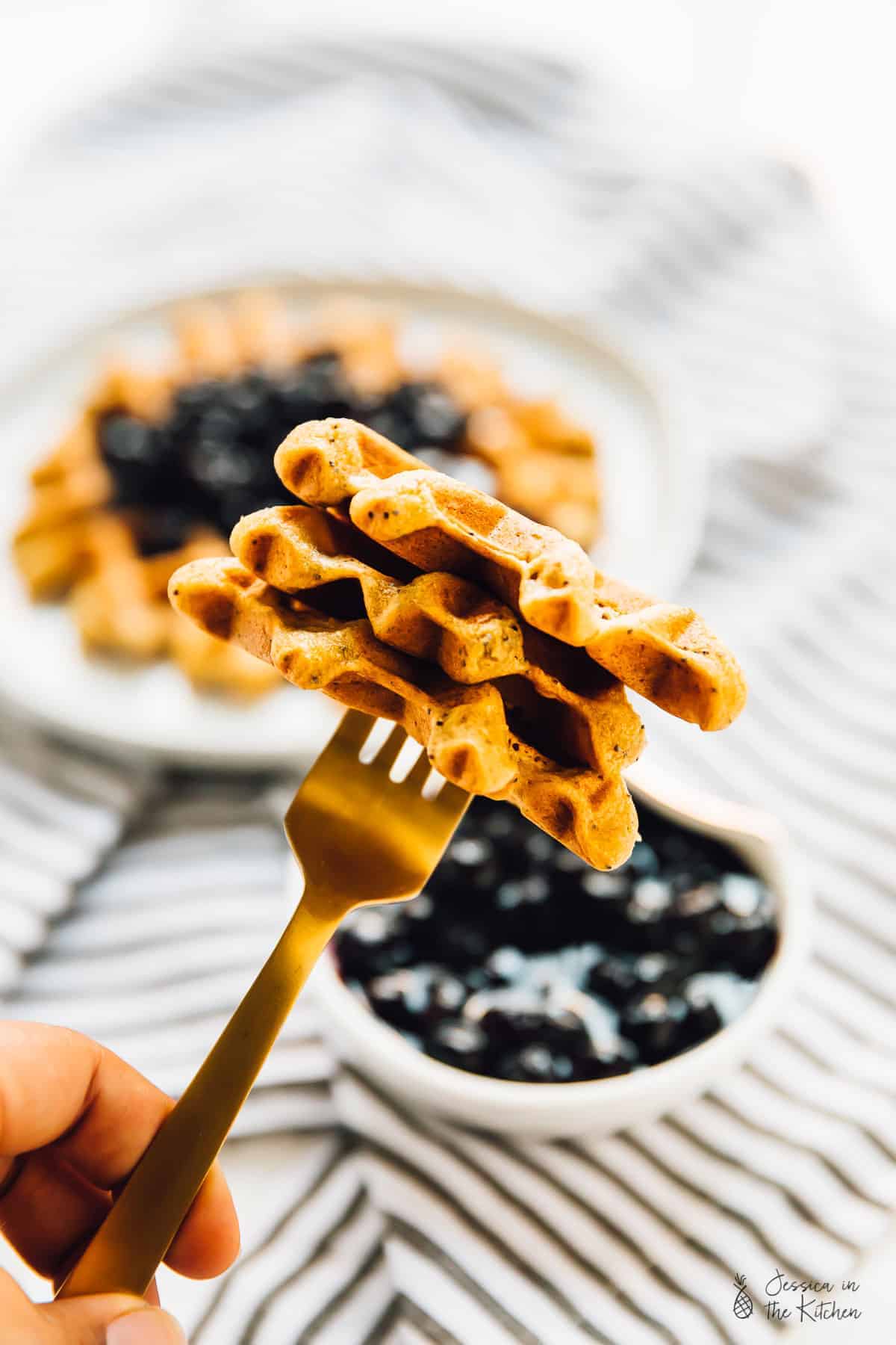 A portion of lemon poppyseed waffle on a gold fork. 