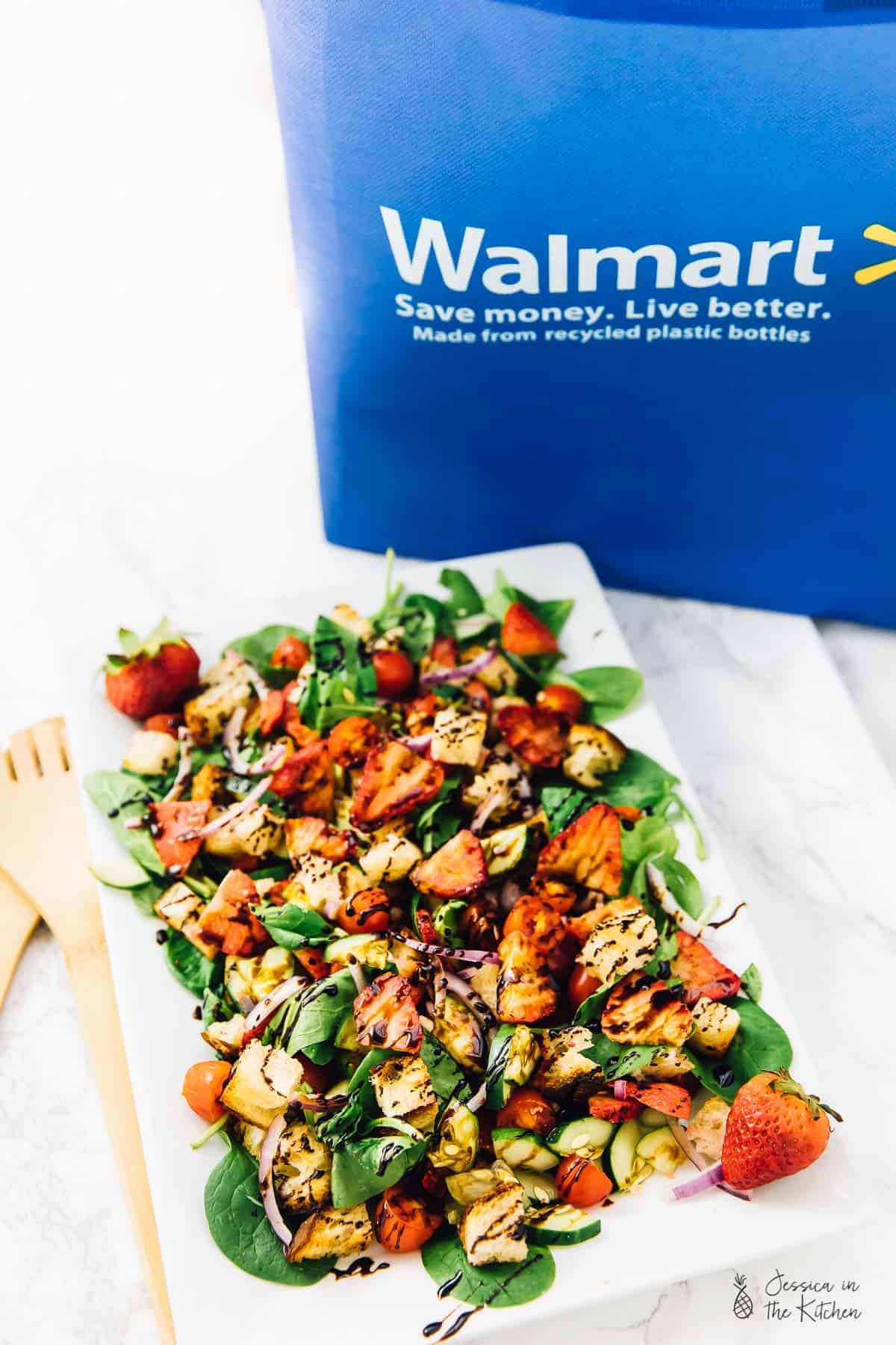 Strawberry panzanella salad with a walmart bag behind it. 