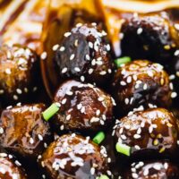 A spoon stirring vegan teriyaki meatballs.