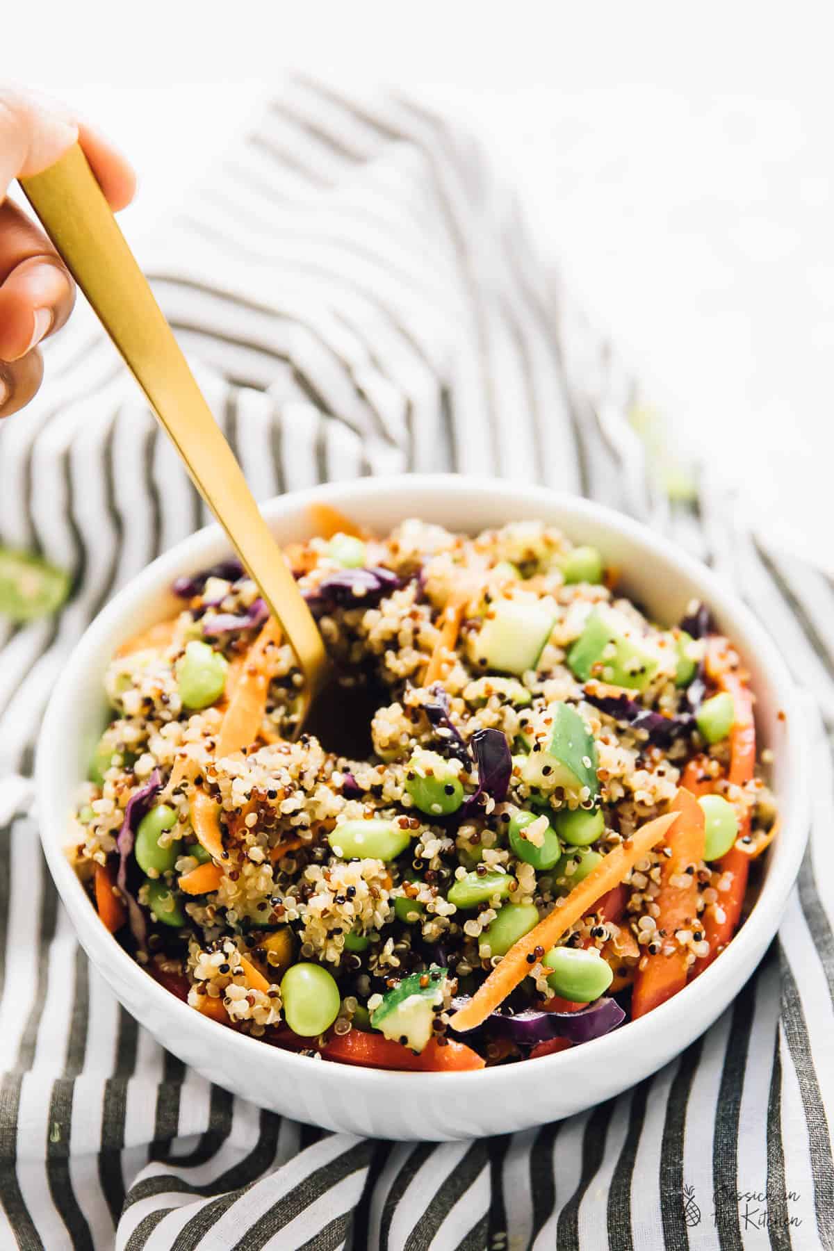 Gold spoon digging into bowl of Asian quinoa salad