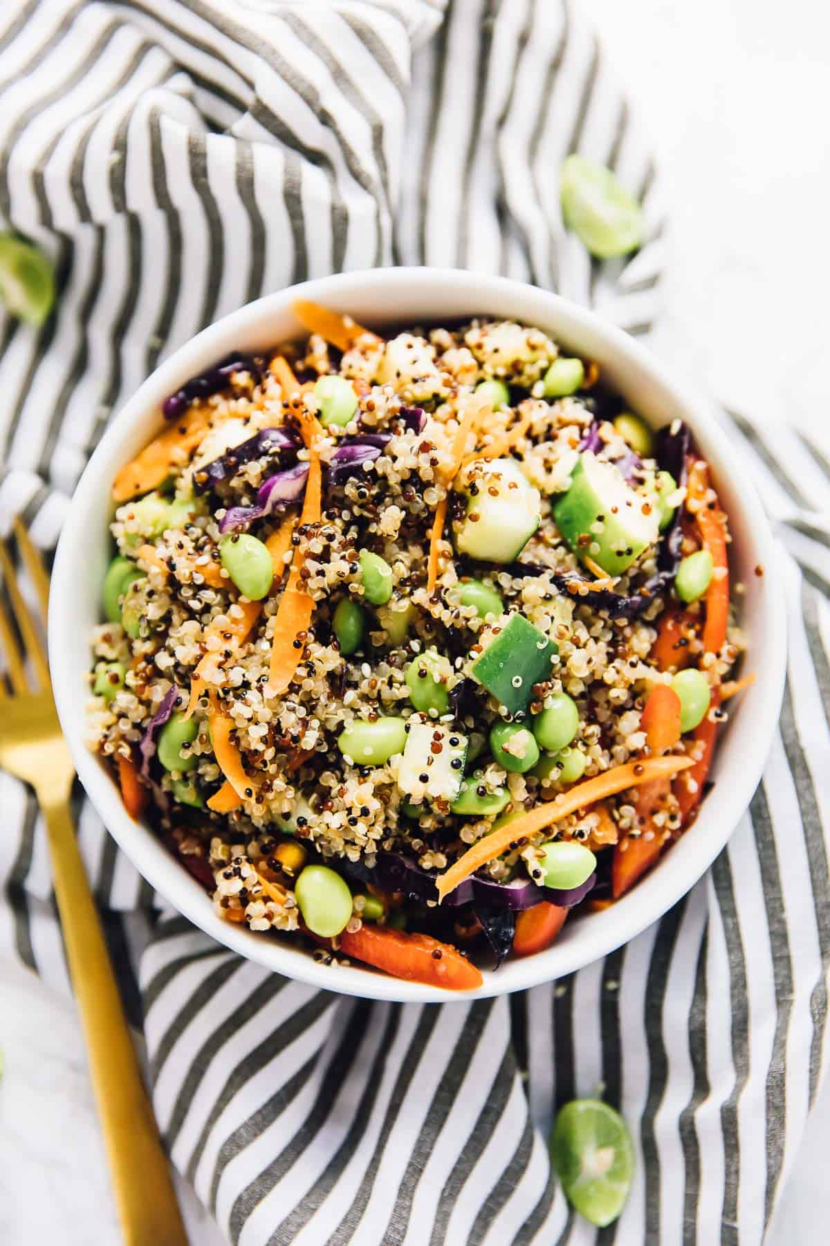 Top down view of asian quinoa salad in a bowl, with a gold fork on the side. 