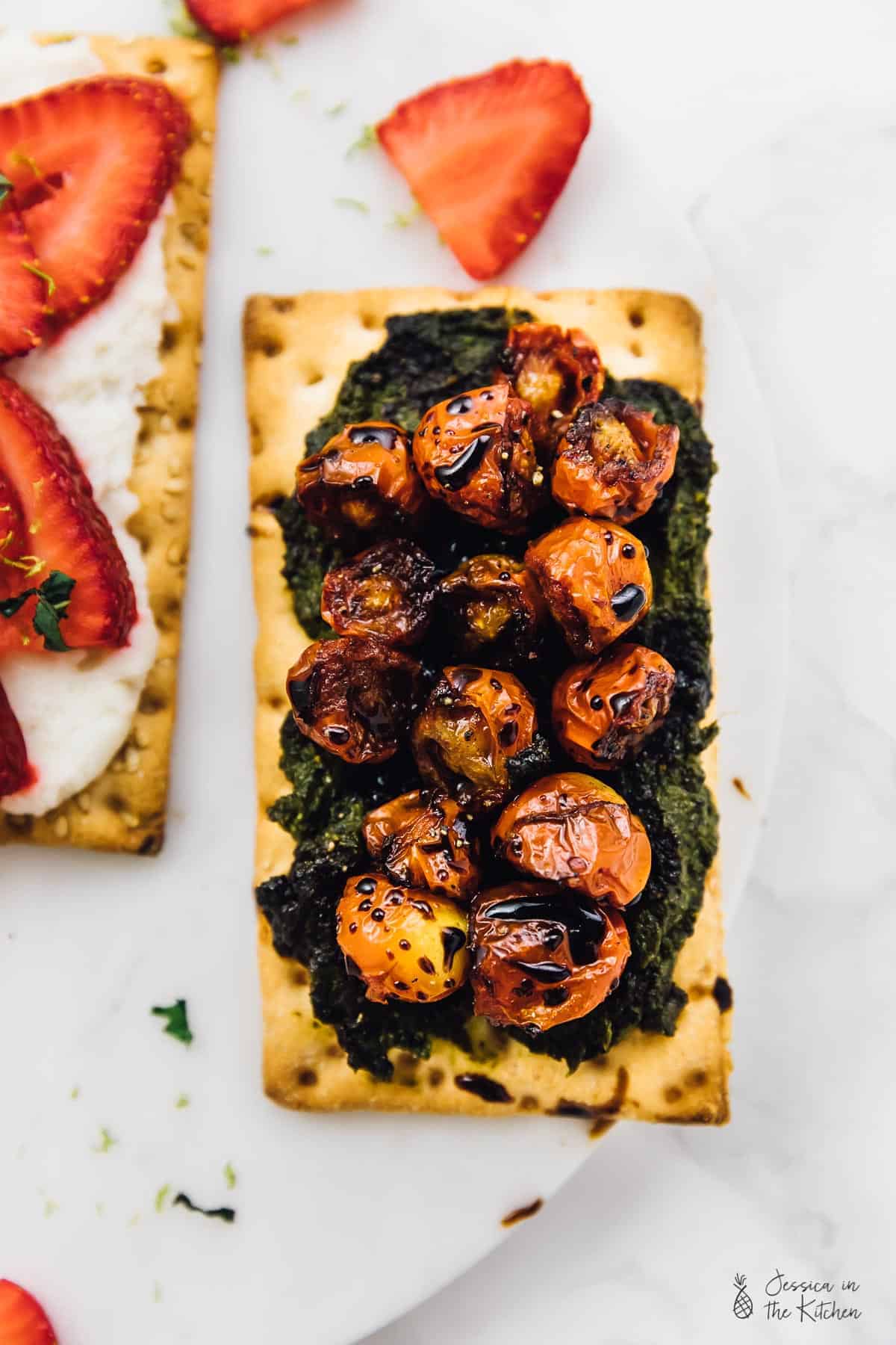 Top down view of pesto and cherry tomatoes on a crisp bread. 
