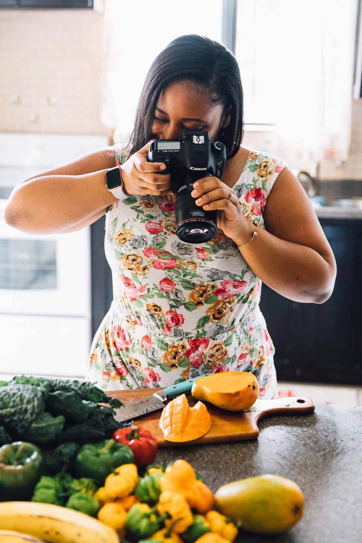 Jessica taking a picture of a mango in a kitchen. 