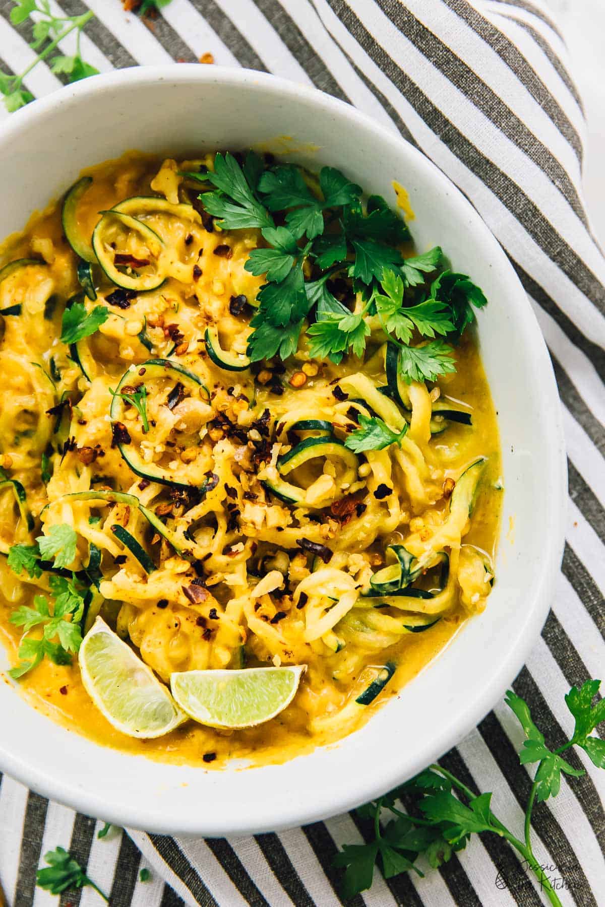 Top down view of a curried satay veggie bowl in striped cloth. 