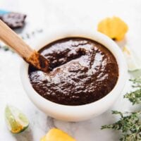 Jamaica jerk sauce in a white bowl with wooden spoon sticking out.