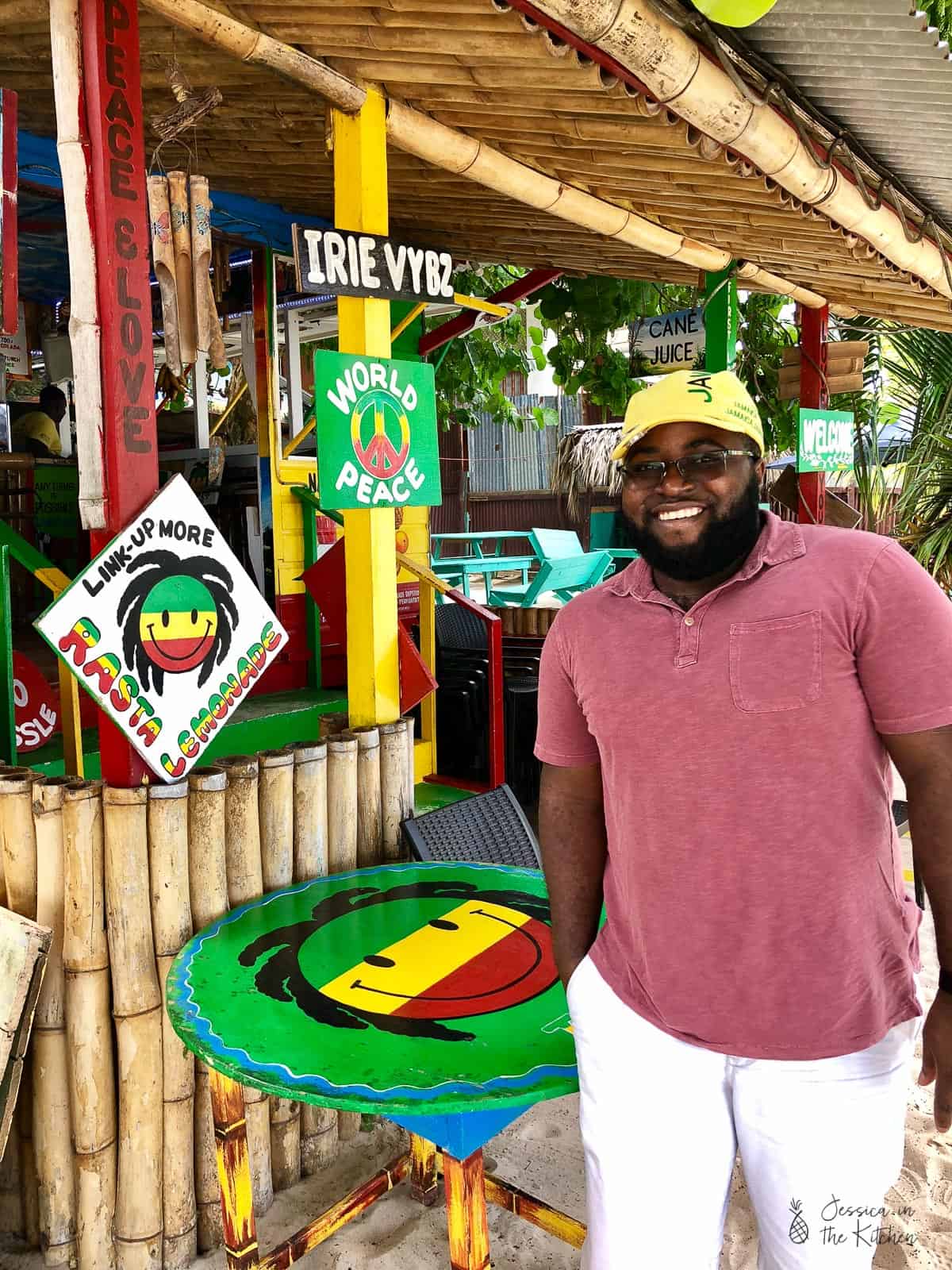 A man in a pink shirt standing next to a bamboo bar. 