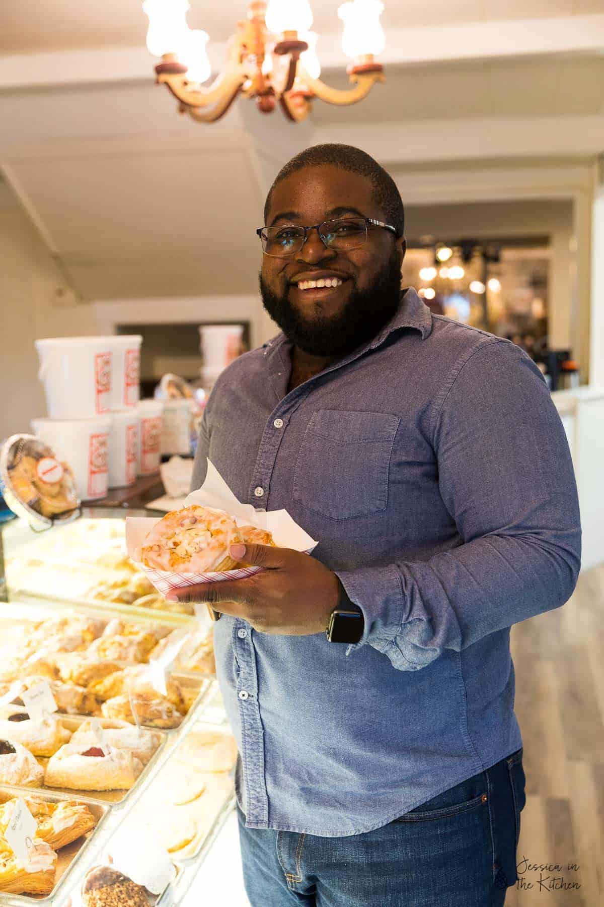 Gavin holding some pastries, smiling. 