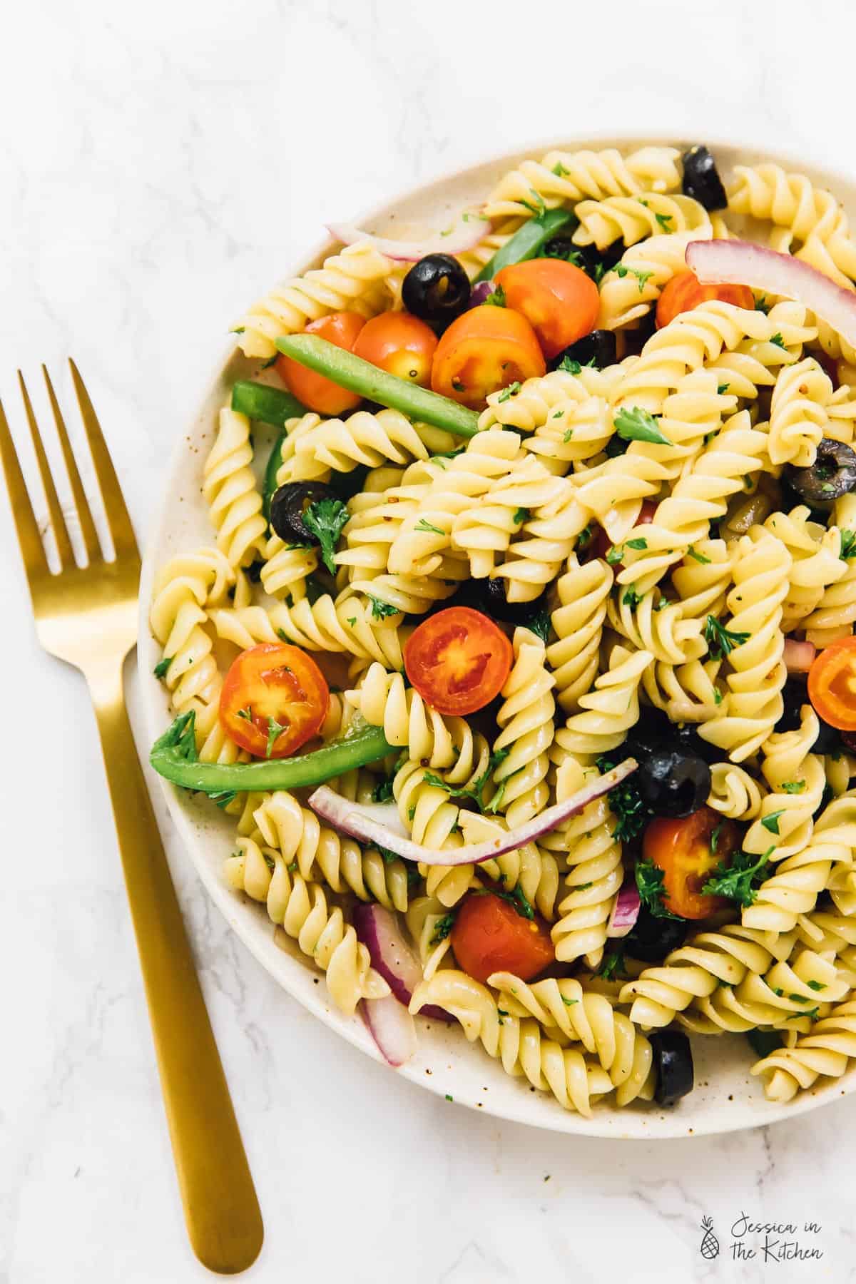 Top down view of vegan pasta salad with a gold fork on the side. 