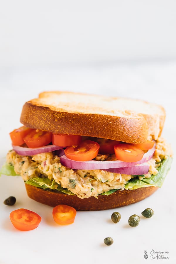 A chickpea tuna sandwich with sliced tomatoes and onions. 