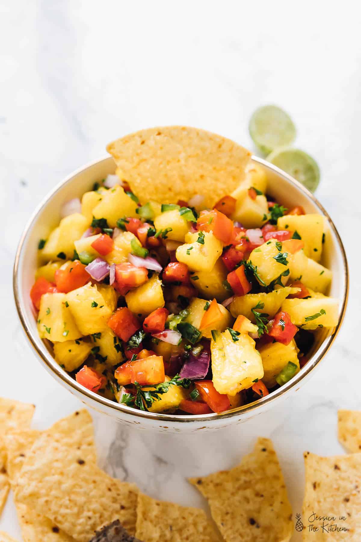Pineapple salsa in a small bowl with a chip dipped in.