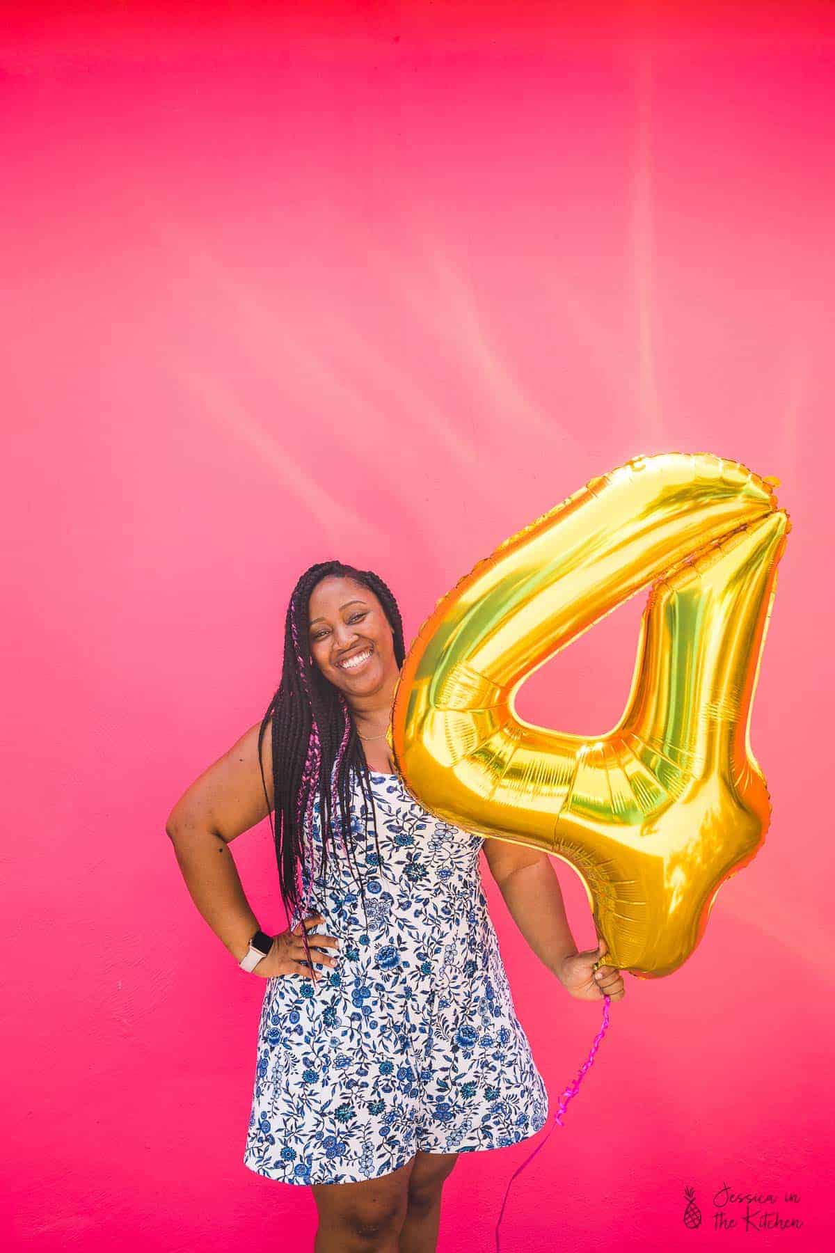 Jessica smiling and holding a four balloon. 