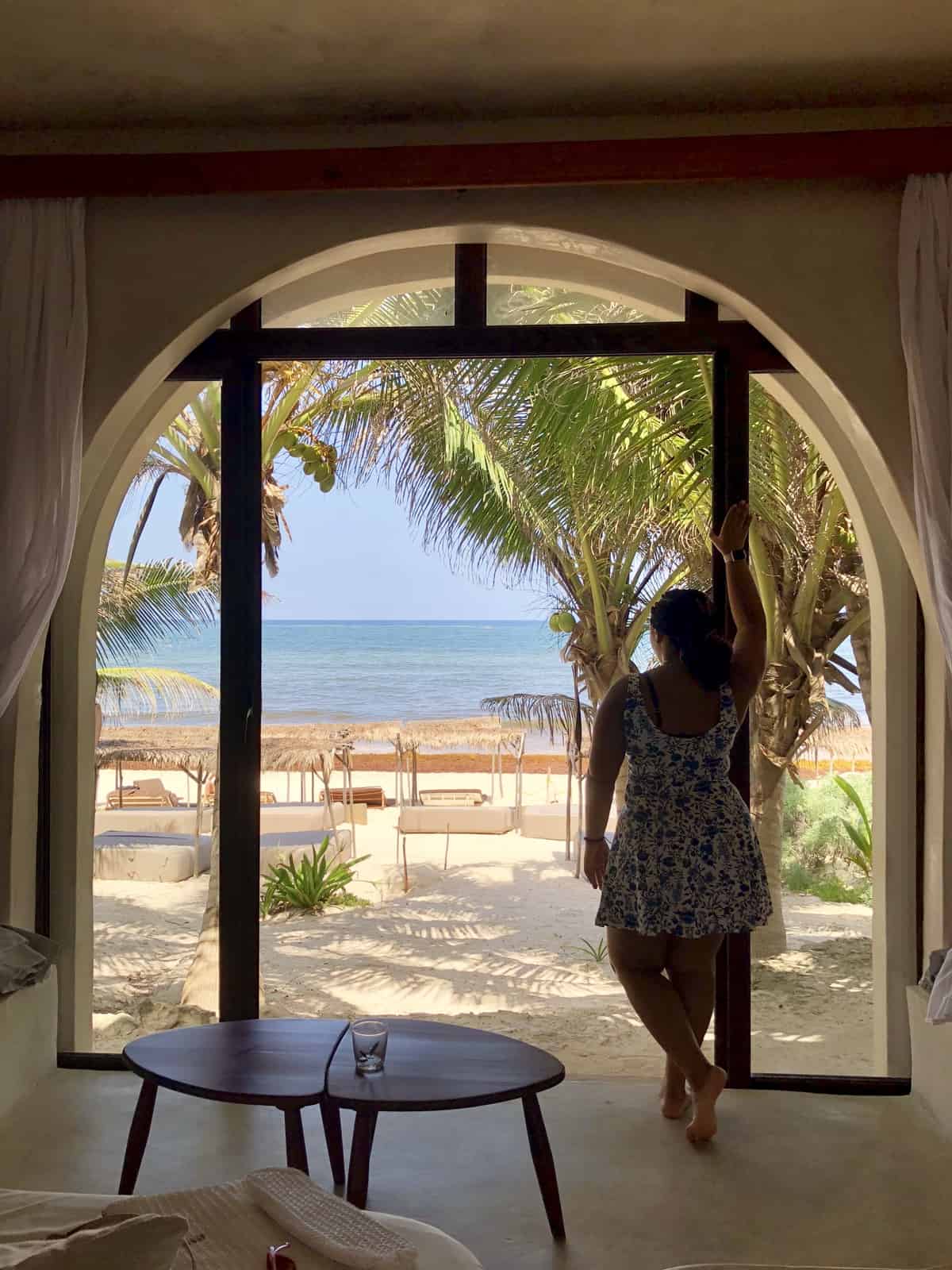 Jessica looking out from hotel room onto a beach. 