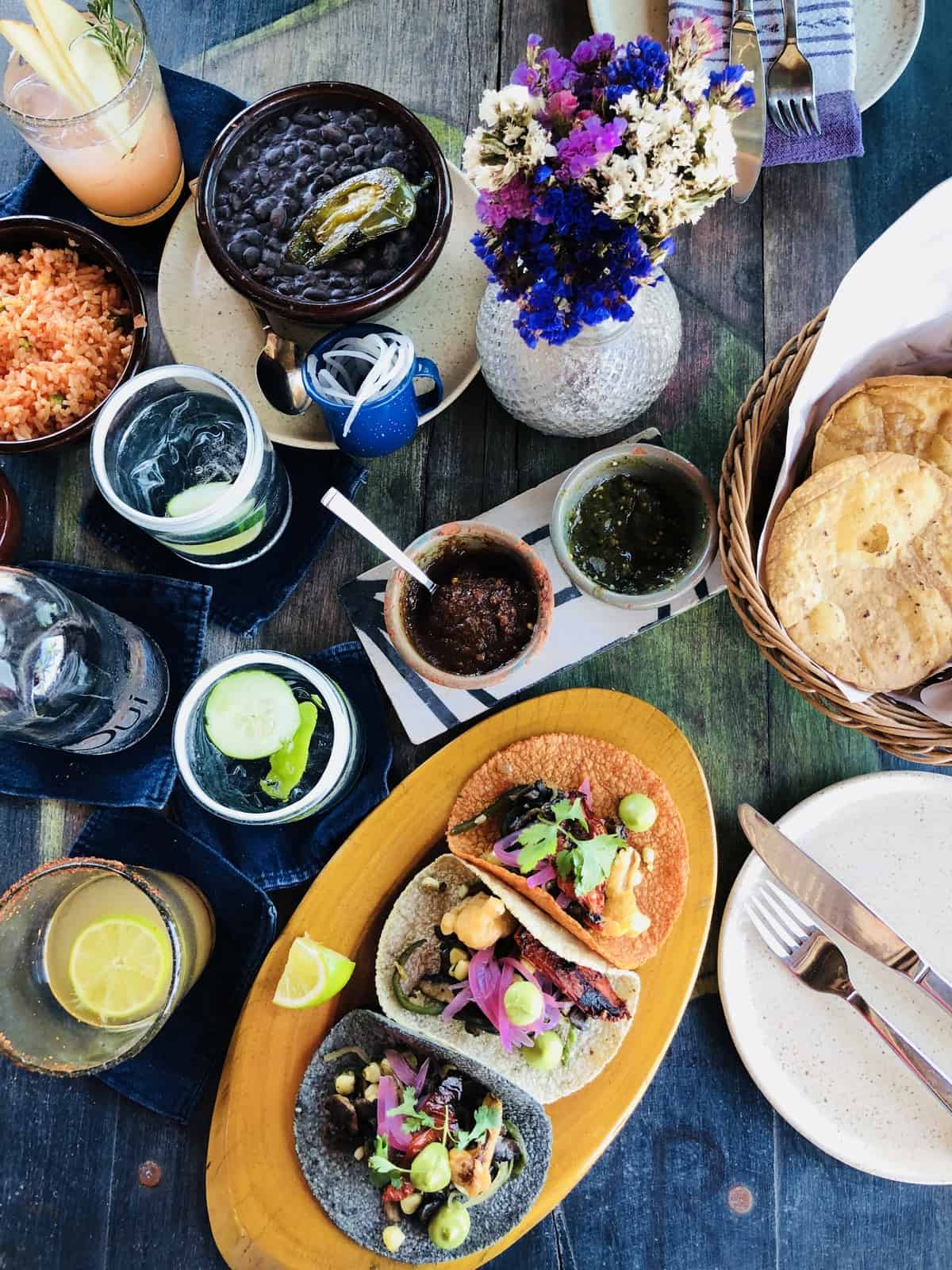 Top down view of drinks, sauces and tacos on a table. 