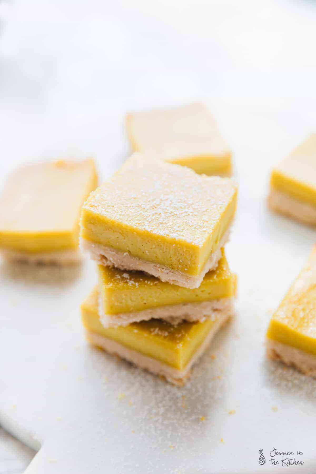 A stack of vegan lemon bars, surrounded by more bars. 