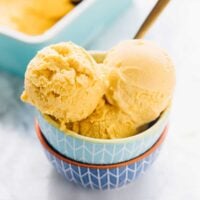 Three scoops of mango ice cream in a bowl.
