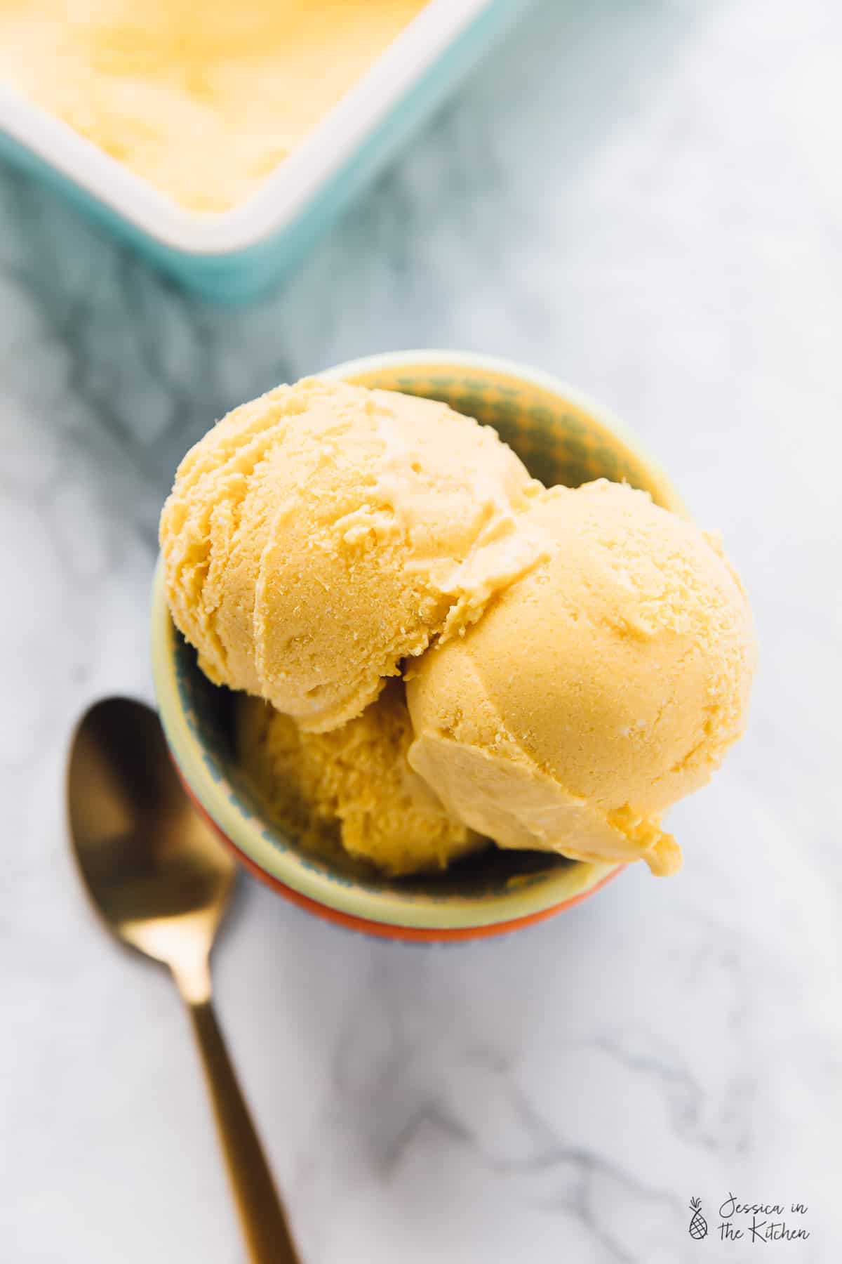 Overhead view of mango ice cream scoops in bowl