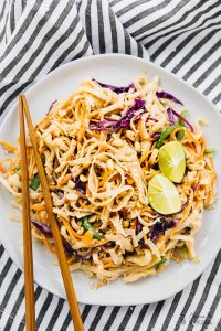 Asian noodle salad on a plate with chopsticks on the side.