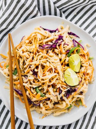 Asian noodle salad on a plate with chopsticks on the side.