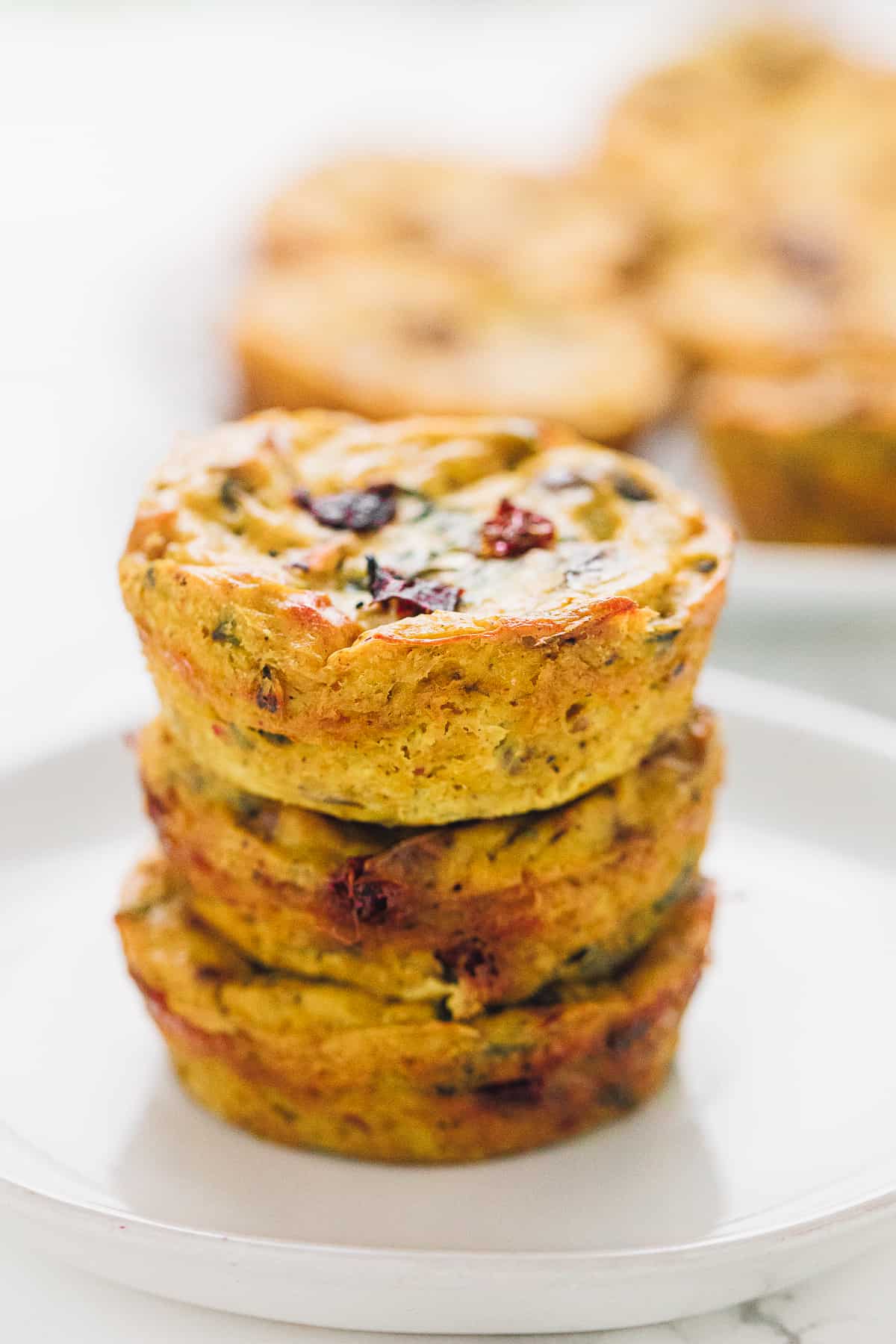 3 vegan quiche muffins stacked on a white plate close up