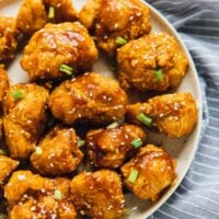 Overhead view of sweet and sticky orange cauliflower bites on a grey plate.
