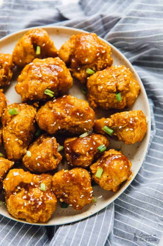 Overhead view of sweet and sticky orange cauliflower bites on a grey plate.