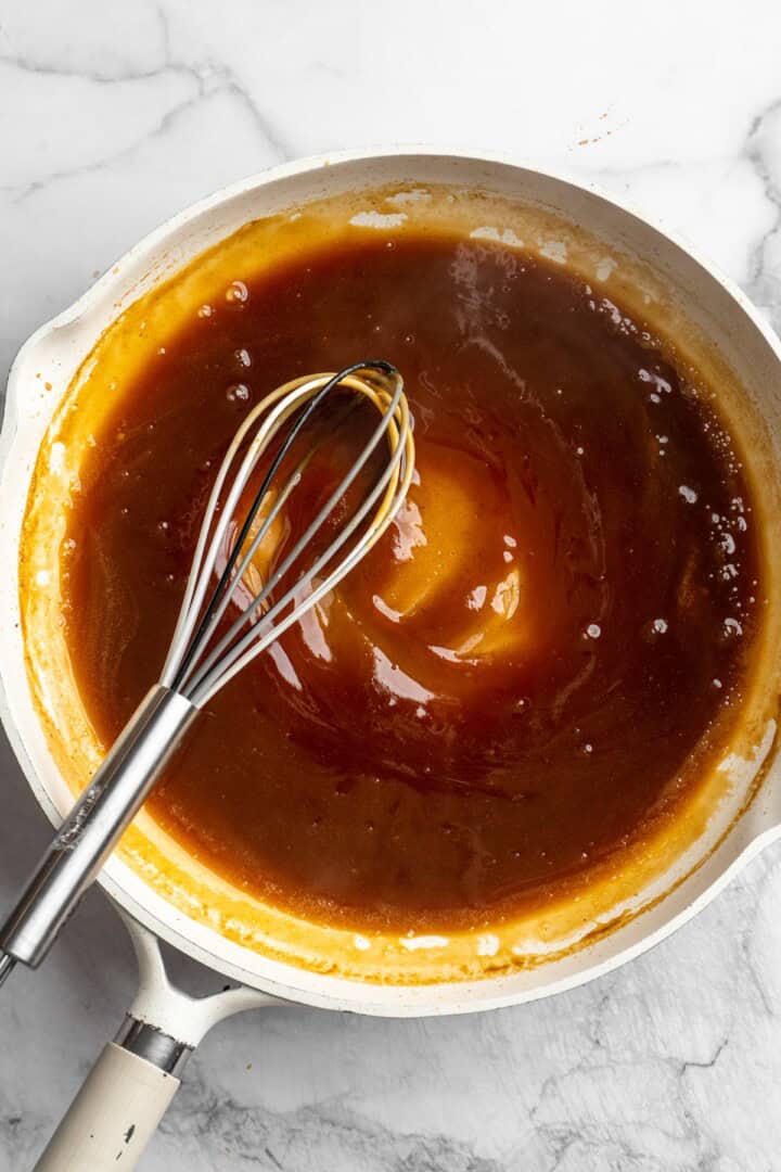 Overhead view of orange sauce in pan with whisk