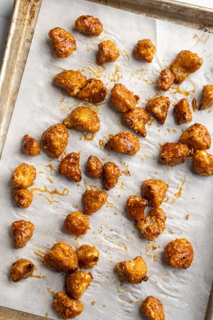 Overhead view of orange cauliflower on parchment-lined sheet pan