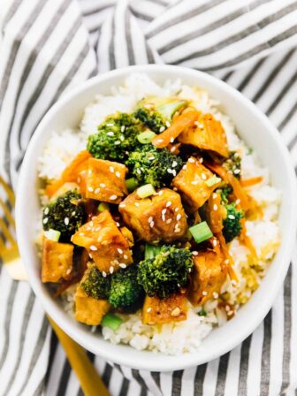 Tofu and broccoli and carrots in a stir fry on top of a bed of rice.