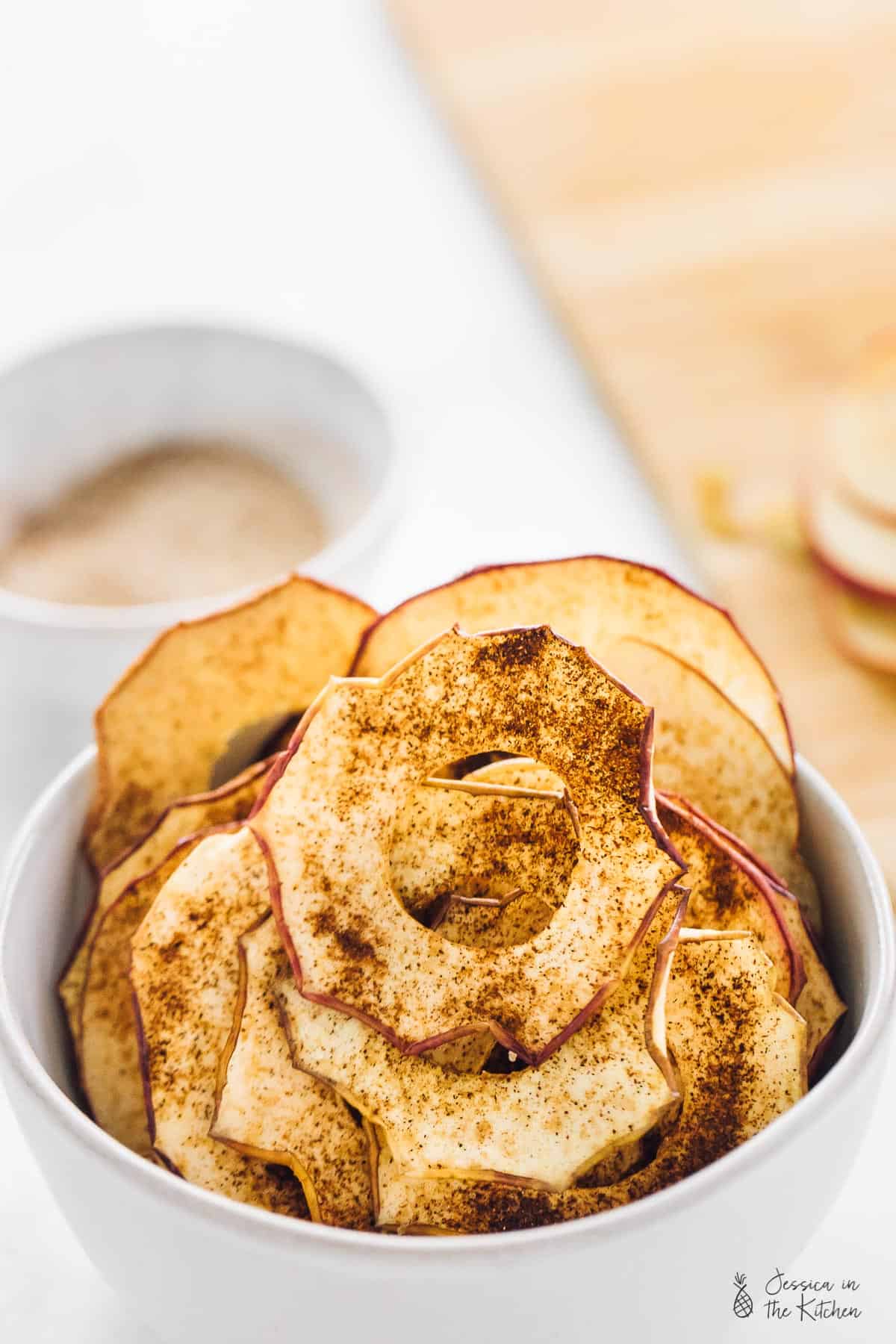 Close up of a bowl of apple chips covered in cinnamon sugar. 