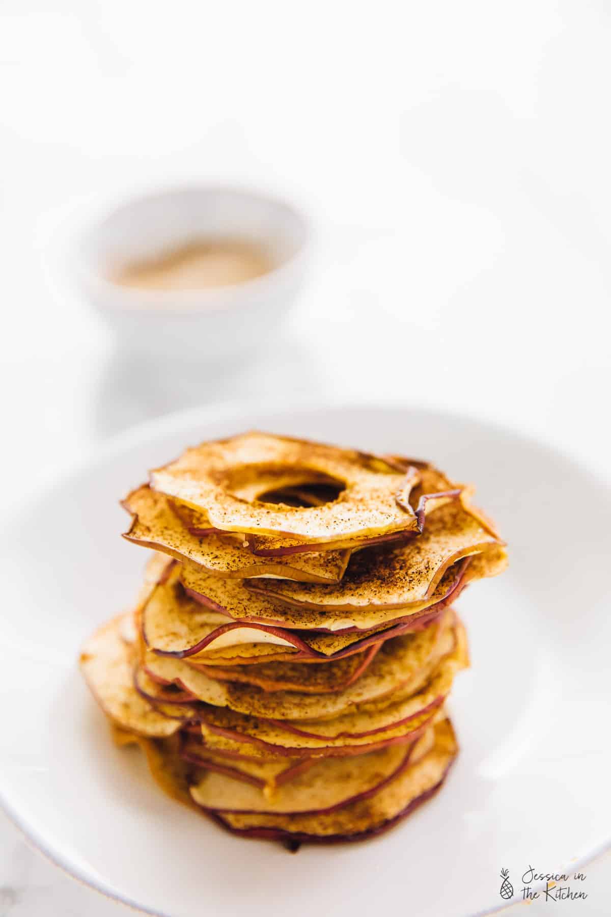 A stack of cinnamon apple chips on a white plate. 