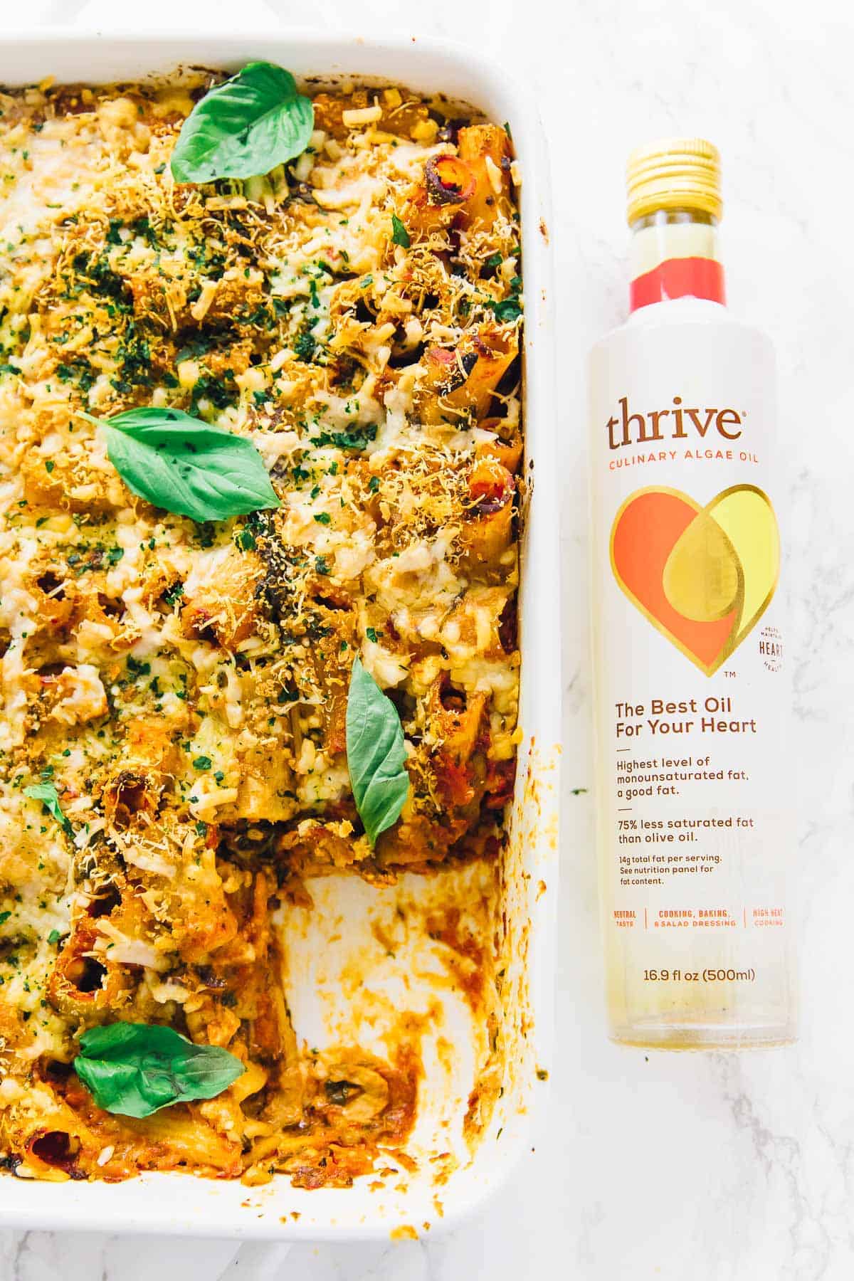 Vegan cheese pasta bake next to a bottle of algae oil.