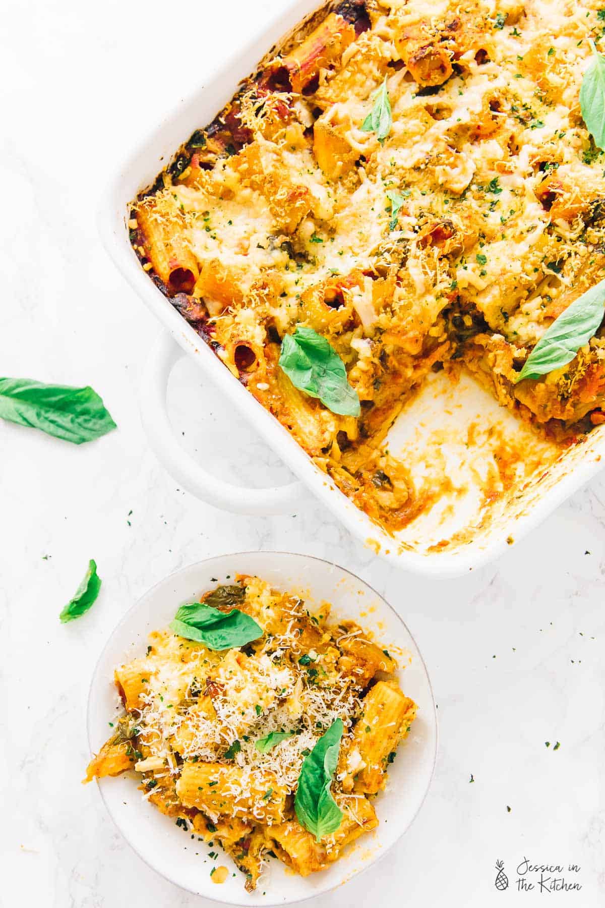 Top down view of vegan cheese pasta bake on a plate and in a baking dish. 