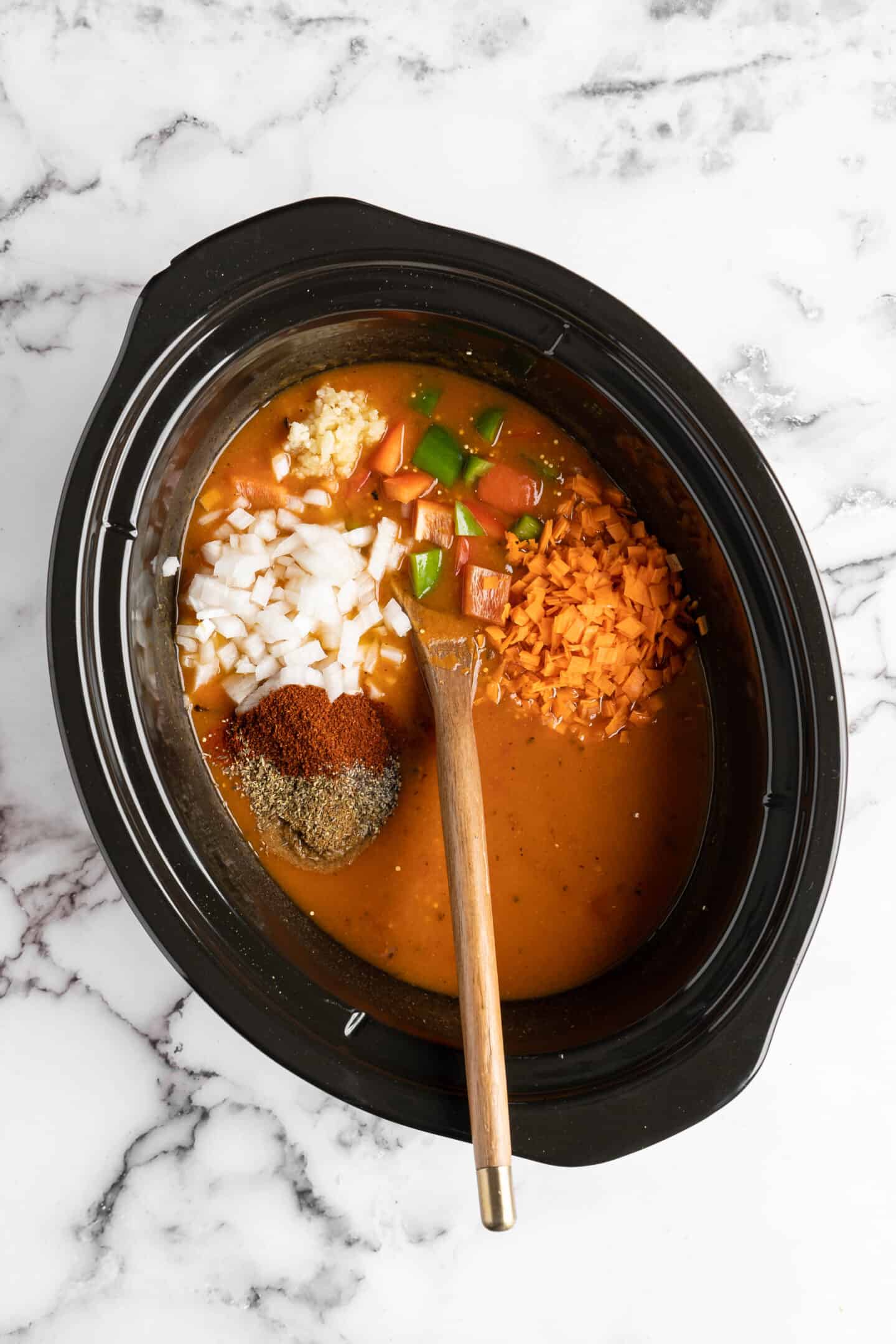 Adding ingredients for pumpkin chili into a slow cooker