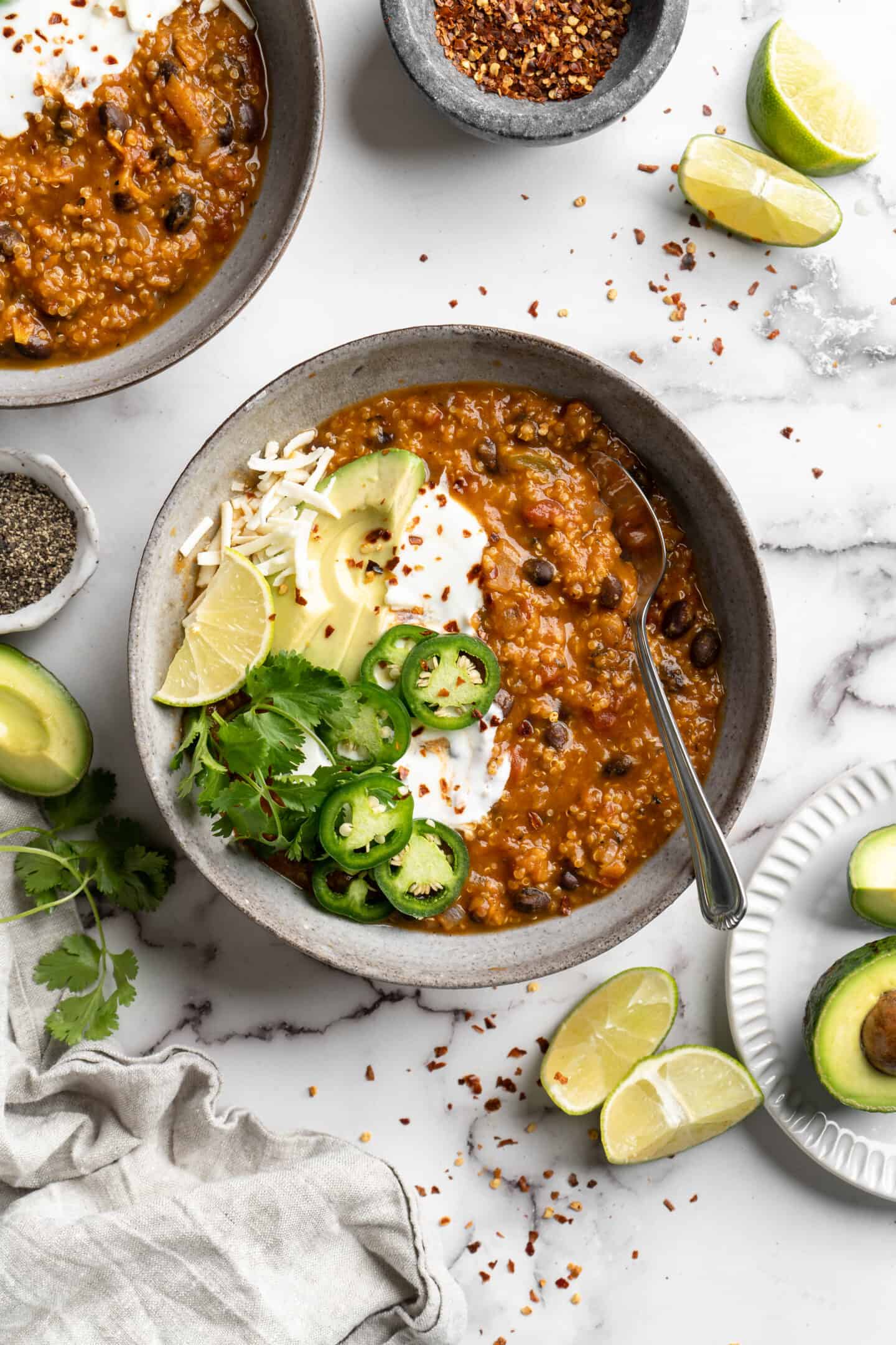 Bowl of pumpkin chili topped with jalapenos and avocado