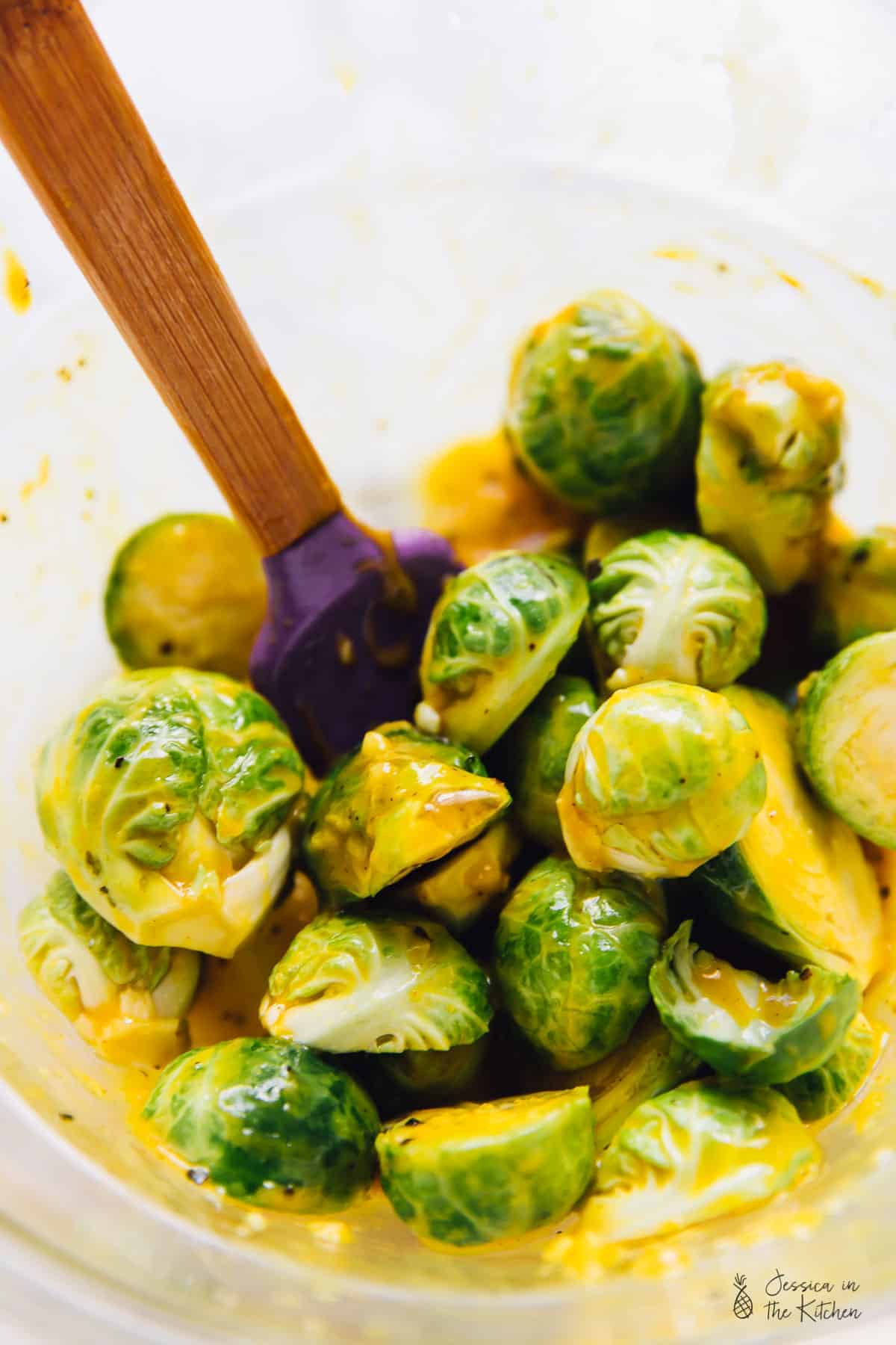 Mixing brussels sprouts with maple mustard dressing. 