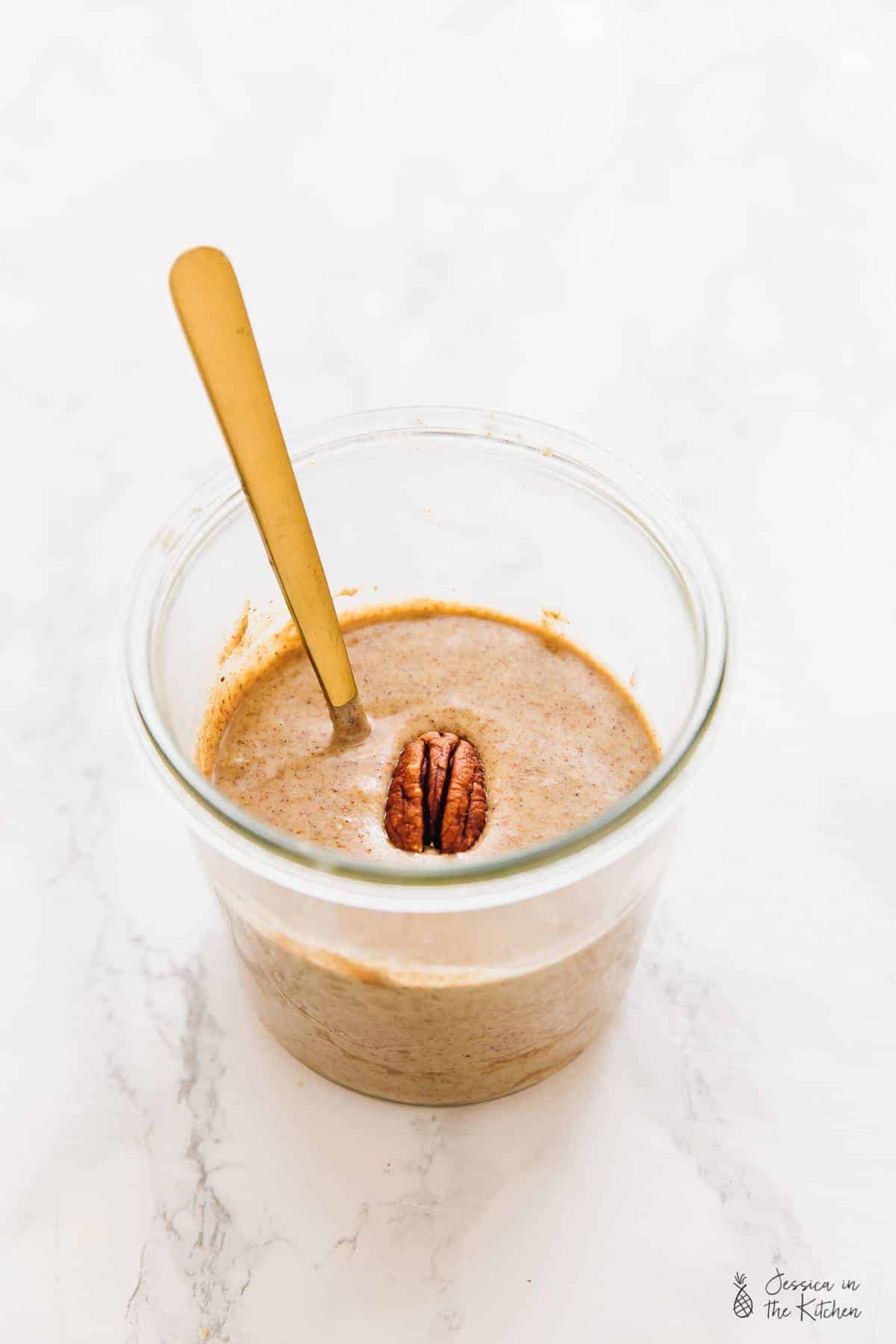 Pecan butter in a glass, with a gold spoon. 