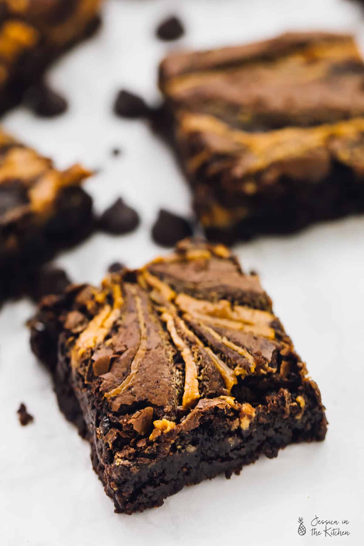 Close up of vegan brownies, surrounded by chocolate chips. 