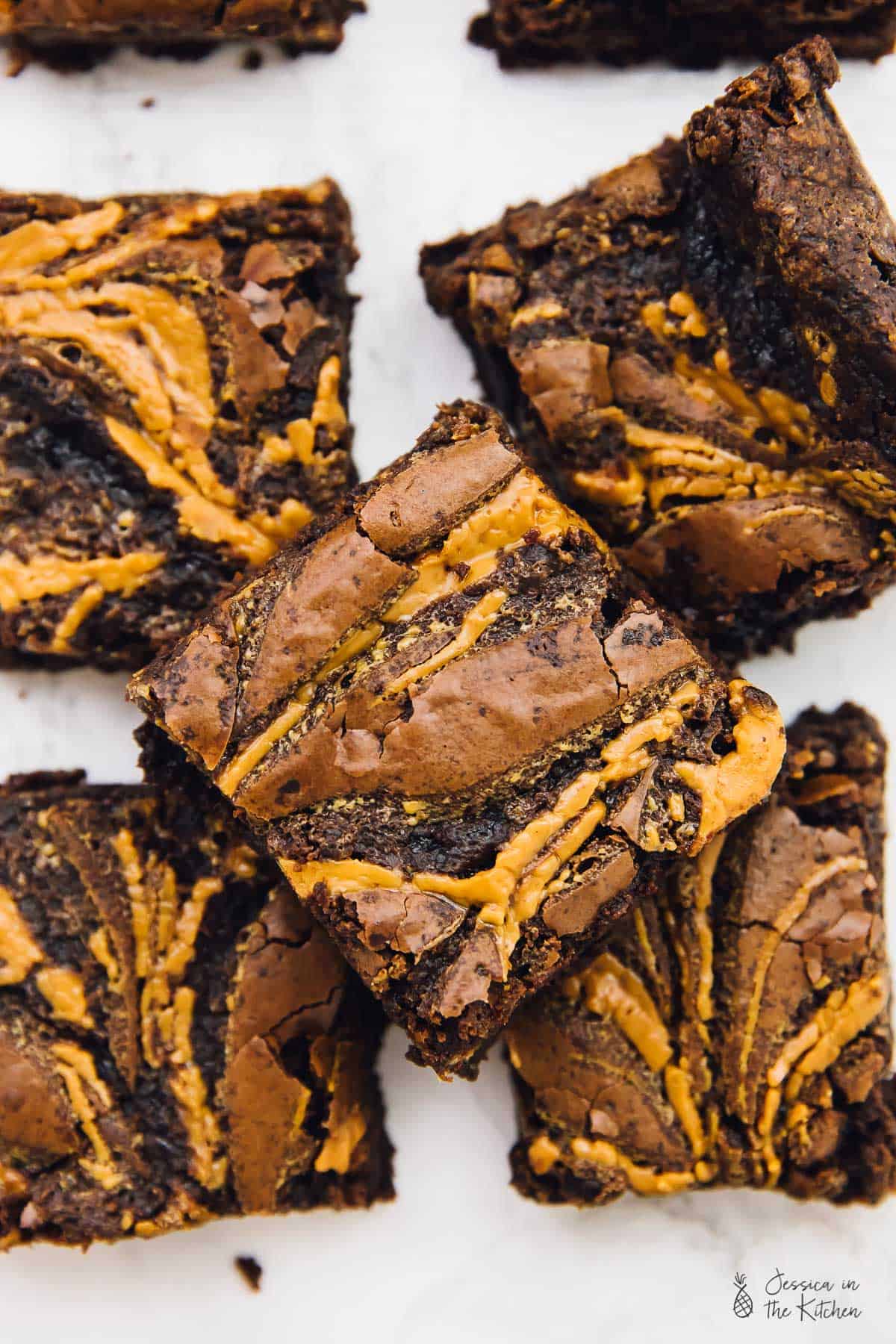 Top down view of vegan chocolate peanut butter swirl brownies on a white table. 