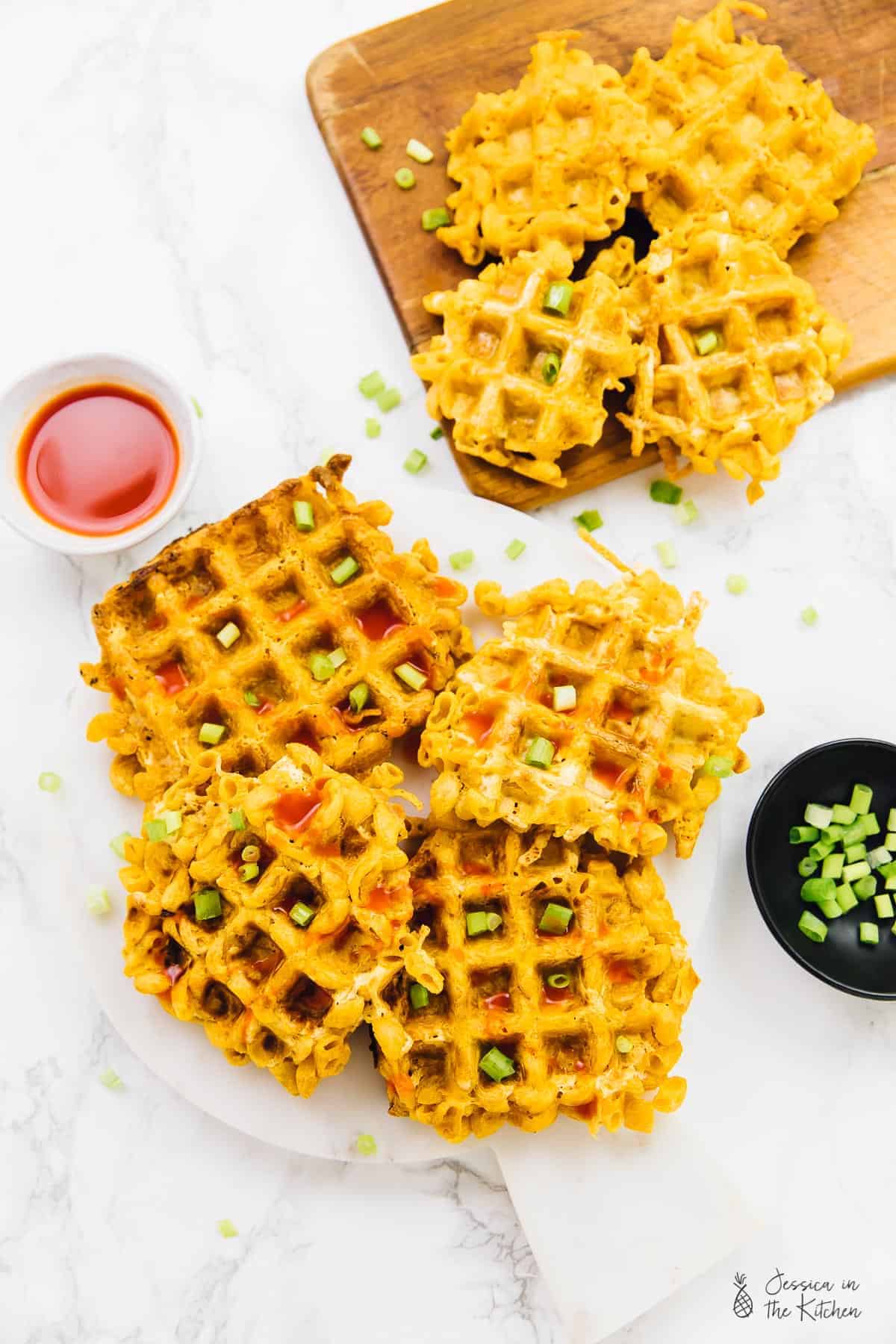 Overhead view of mac and cheese waffles on a plate and a board. 