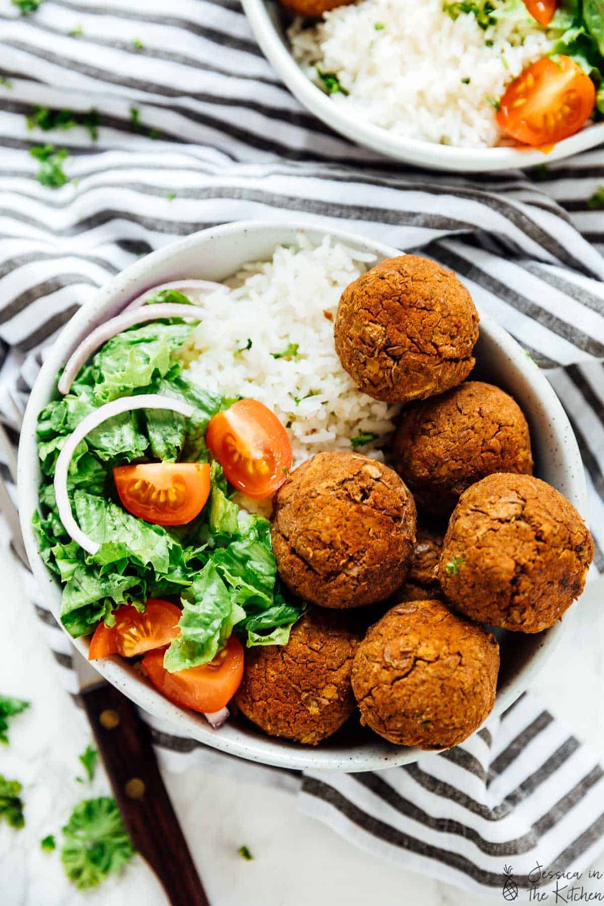 Top down view of a bowl of lentil balls with zesty rice and salad.