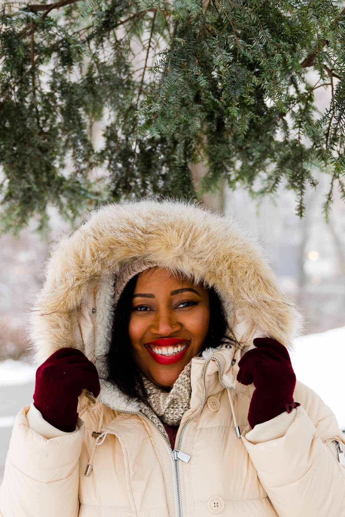Jessica under a tree in the snow, smiling to camera. 