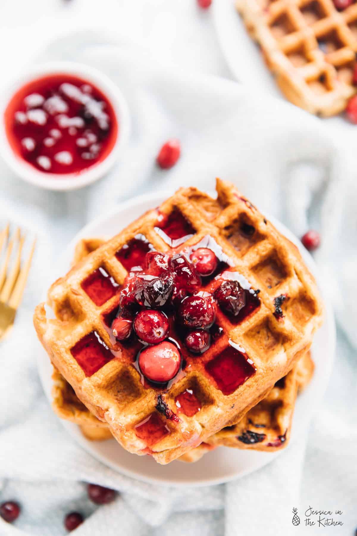 Top down view of orange cranberry waffles covered in syrup. 