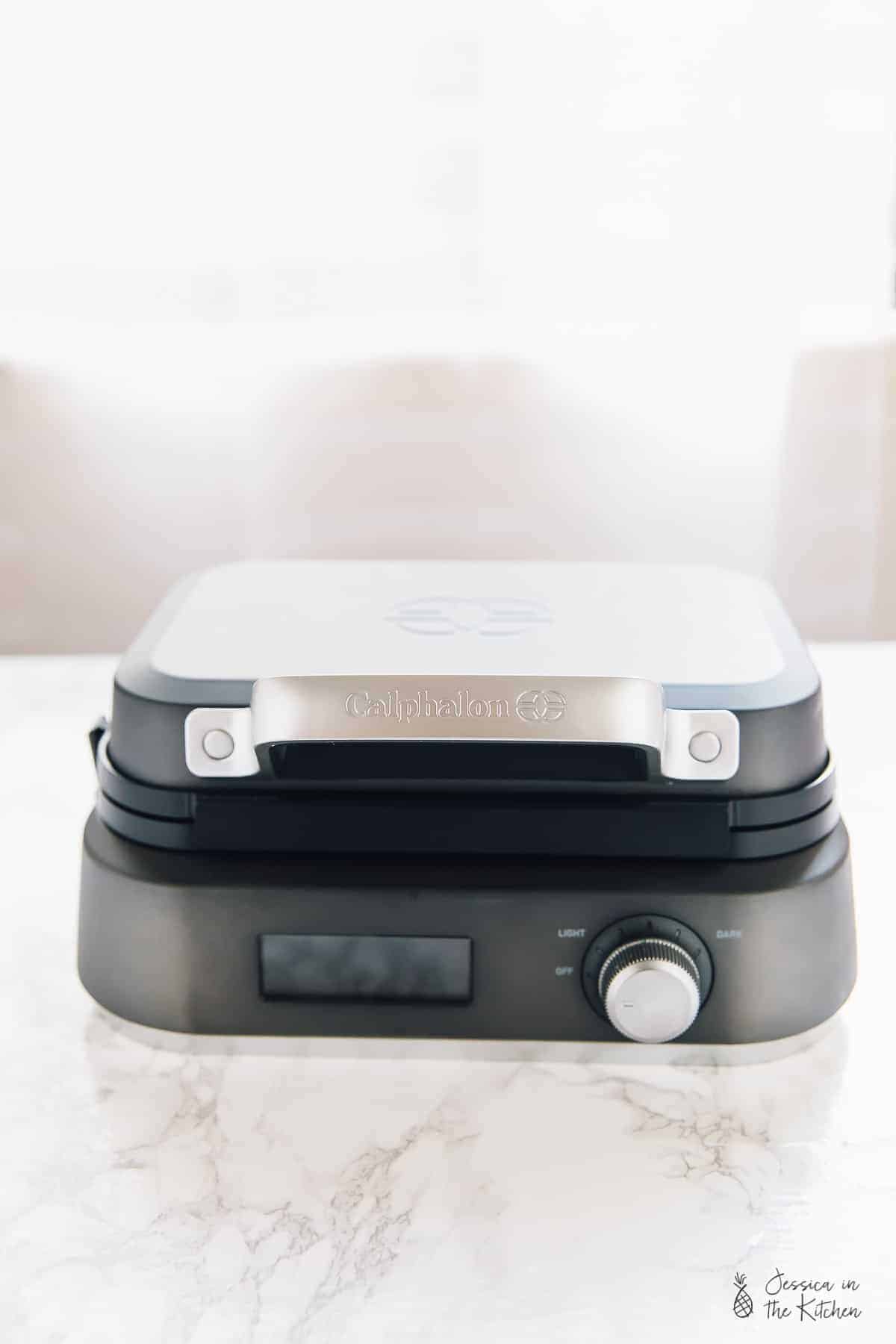Side shot of a waffle maker on a table. 